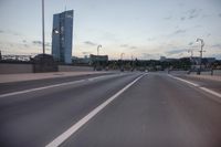 the street is empty with cars and lights on the side of it at night time