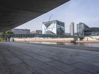 an empty walkway next to a lake in the middle of the city with tall buildings