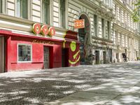 a restaurant in the middle of a narrow city street with graffiti on the wall and the sidewalk outside the building