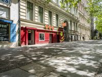 a restaurant in the middle of a narrow city street with graffiti on the wall and the sidewalk outside the building