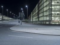 a parking lot with several lights along a street and an empty sidewalk near it at night