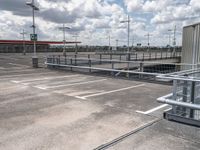 an empty parking lot with several cars parked outside of the building and a street light above them