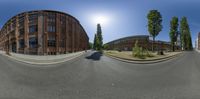 a long road with some buildings around it and blue sky in the background by some grass