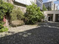 empty cobblestone path surrounded by greenery in public park area with building in background