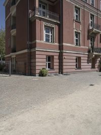 a woman with a cell phone is walking across a gravel driveway next to two older buildings