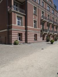 a woman with a cell phone is walking across a gravel driveway next to two older buildings