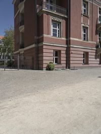 a woman with a cell phone is walking across a gravel driveway next to two older buildings