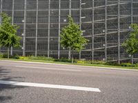 the street is empty and some trees near it, along with a building behind it