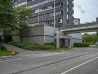 a long narrow highway going under an elevated street bridge with cars passing underneath it and a car driving up the hill