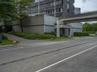 a long narrow highway going under an elevated street bridge with cars passing underneath it and a car driving up the hill