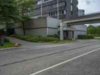 a long narrow highway going under an elevated street bridge with cars passing underneath it and a car driving up the hill