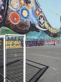 a painting of an elephant is shown in a parking lot outside a fenced area