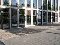 people walking in front of a building with glass windows with sun shining in the reflection