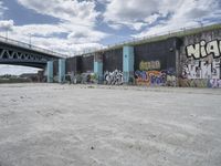 a large concrete wall with graffiti on it with the sun behind it and a blue sky