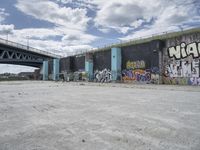 a large concrete wall with graffiti on it with the sun behind it and a blue sky