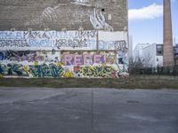 graffiti on the side of a building with a brick chimney in front of it and some green grass