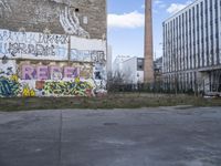 graffiti on the side of a building with a brick chimney in front of it and some green grass