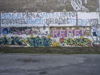 graffiti on the side of a building with a brick chimney in front of it and some green grass