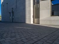 two people walking down an empty city street in an alley area with tall buildings in the background