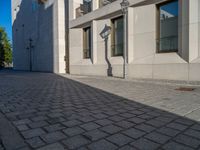 two people walking down an empty city street in an alley area with tall buildings in the background