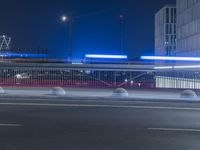 the empty city road is empty by the tall building in the background at night with light streaking on the buildings