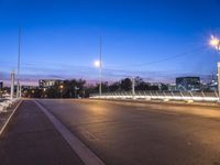 the city lights and an empty sidewalk are on a purple sky day with clouds above