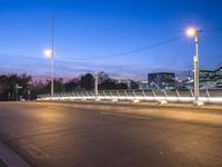 the city lights and an empty sidewalk are on a purple sky day with clouds above