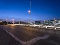 the city lights and an empty sidewalk are on a purple sky day with clouds above