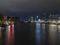 a nighttime view of a river and lights on buildings in the background at night with city lights