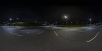 a street in a roundabout at night with traffic lights shining overhead and dark skies above