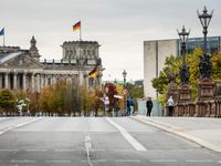 people walking down a city street, with a statue of the reichland in the background