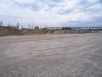 a lot of sand on the ground with trucks in the background and two buildings under construction