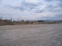 a lot of sand on the ground with trucks in the background and two buildings under construction