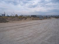 a lot of sand on the ground with trucks in the background and two buildings under construction