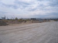 a lot of sand on the ground with trucks in the background and two buildings under construction