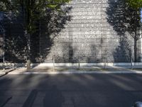 a fire hydrant and a wall with trees by it, as if in the morning