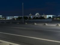 large building on the street with lights in front and other buildings nearby at night with no one moving