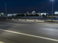 large building on the street with lights in front and other buildings nearby at night with no one moving