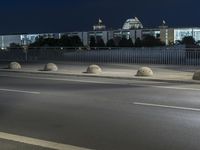 large building on the street with lights in front and other buildings nearby at night with no one moving