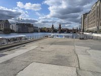 the walkway is empty in the city and is overlooking the river below it are buildings and cars