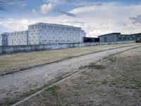 a grassy field in front of some white buildings on a blue cloudy day in summer