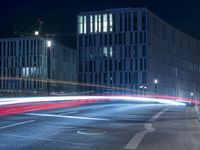 large building on the street with lights in front and other buildings nearby at night with no one moving