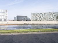 three buildings sitting next to each other near a river and lawn area in front of them