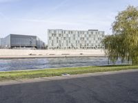 three buildings sitting next to each other near a river and lawn area in front of them