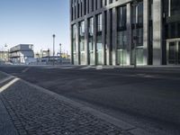 a empty city street next to tall buildings on a clear day, while a traffic light shines bright