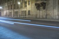 a large building sitting next to a street at night with a light streak on it