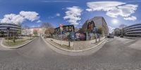 a 360 - shot image of an intersection with cars and buildings around it including murals and people