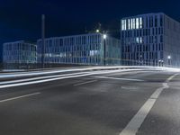 large building on the street with lights in front and other buildings nearby at night with no one moving