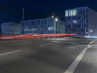 large building on the street with lights in front and other buildings nearby at night with no one moving