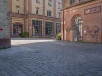 a brick courtyard outside of a large building with an archway at the end of it